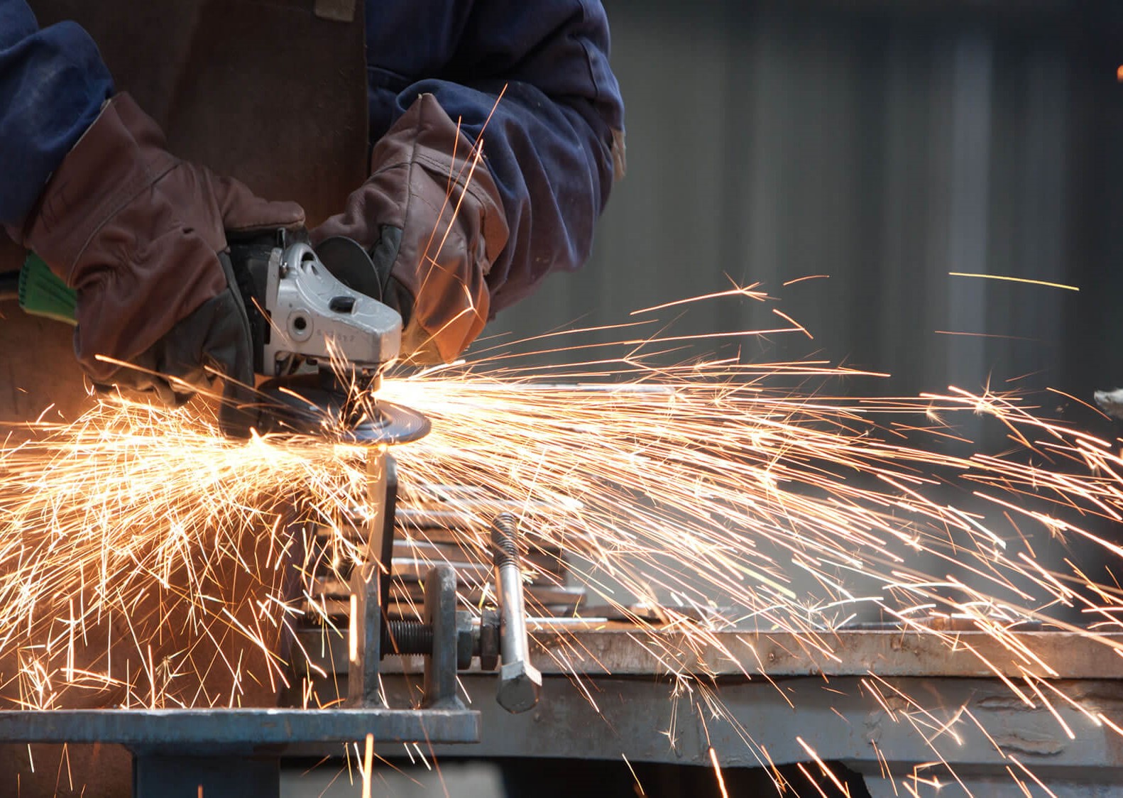 Ein Mann fräst ein Bauteil, es springen Funken